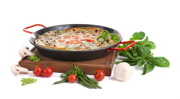 Frittata aux épinards dans la poêle et légumes, isolé sur blanc