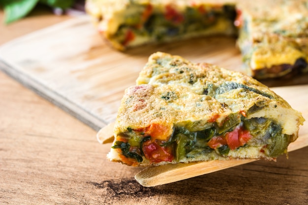 Frittata faite d'oeufs et de légumes sur une table en bois.