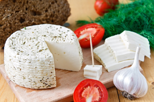 Fromage blanc, pain, tomates et ail sur un fond en bois