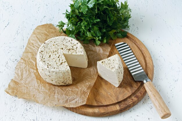 Fromage blanc sur une planche de bois sur un fond blanc avec des verts