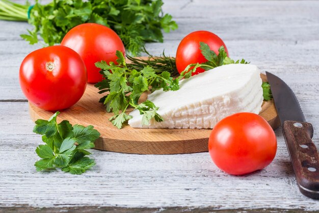 Fromage blanc de saumure, couteau, persil, tomates sur des planches en bois