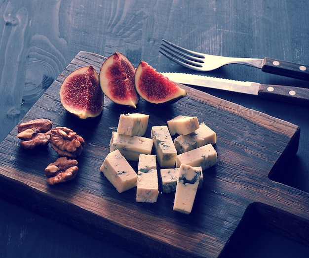 Fromage bleu, figues fraîches et noix sur une planche de bois et un couteau