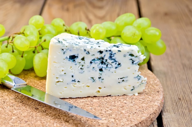 Fromage bleu, raisins, couteau sur planche de bois de fond