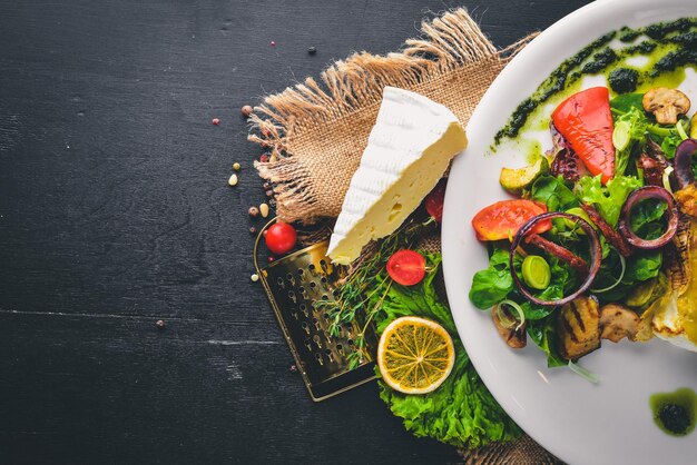 Fromage Brie aux légumes grillés. Vue de dessus. Espace libre pour le texte. Sur un fond en bois.