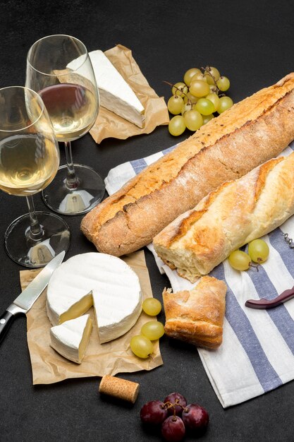 Fromage brie, baguette et deux verres de vin blanc sur fond de béton foncé