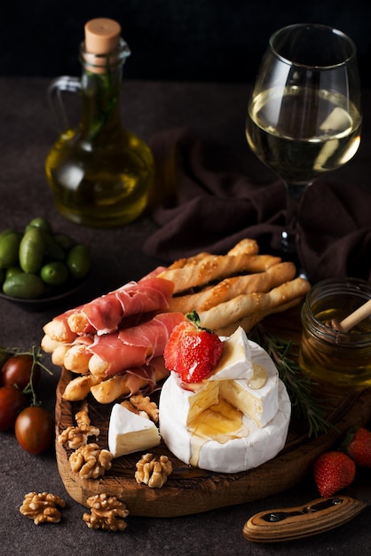 Fromage brie, camembert, grissini, jamon, vin, noix, miel. Snacks pour le vin. Snacks italiens