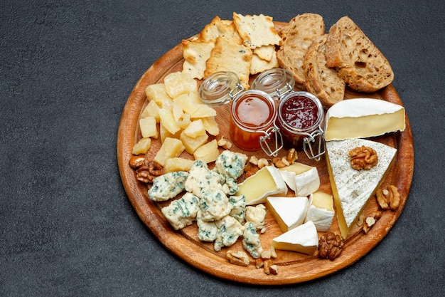 Fromage brie sur une planche de bois avec du pain et de la confiture sucrée