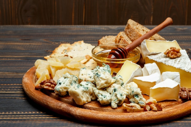 Fromage brie sur une planche de bois avec du pain et du miel doux