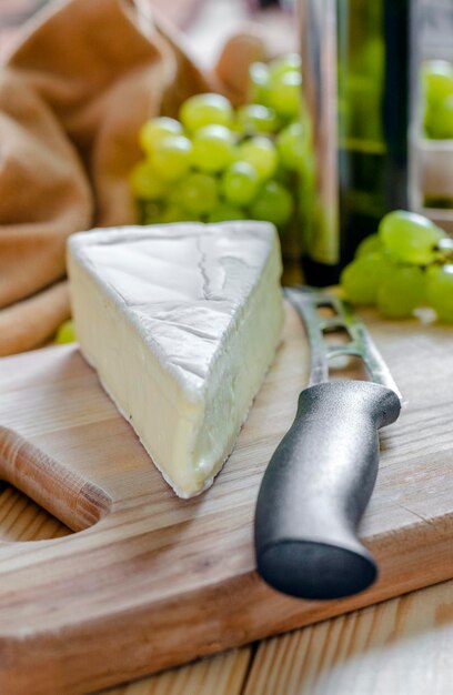 Fromage brie et raisins frais blancs sur une planche en bois