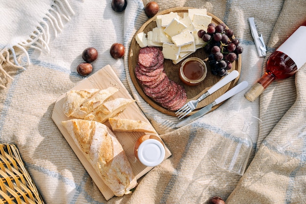 Fromage brie avec salami, raisins et miel sur une planche de bois. Baguette fraîche. Concept de nourriture et de boisson.