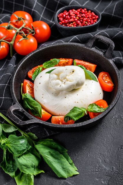 Fromage buffle italien Burrata aux feuilles de basilic et tomates. Caprese Salad. Fond noir. Vue de dessus