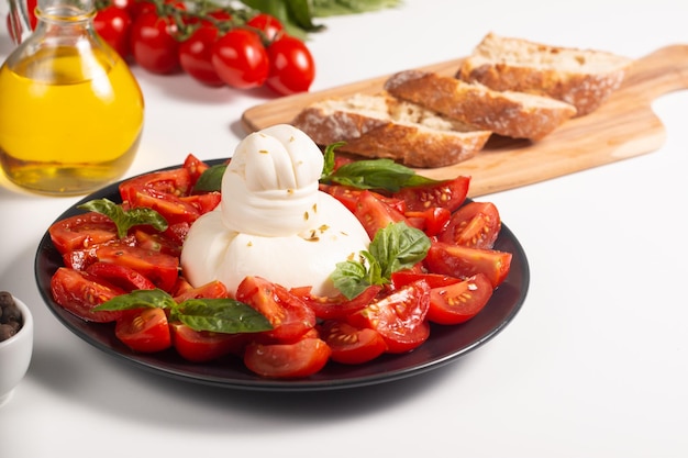 Fromage burrata italien traditionnel avec salade de délicieuses tomates cerises, feuilles de basilic et huile d'olive