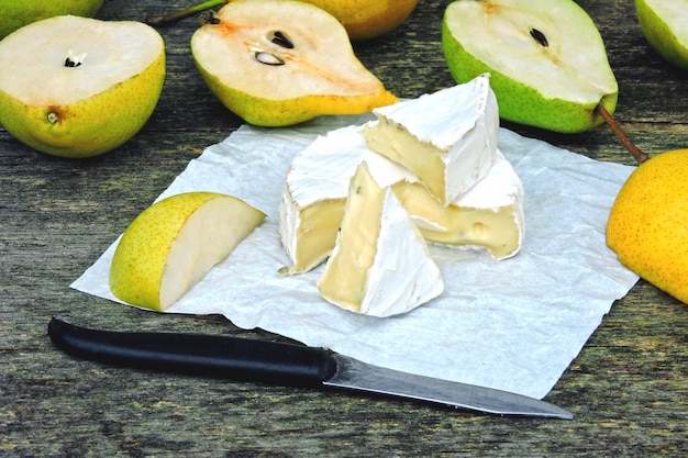 Fromage camembert aux poires sur une surface en bois.