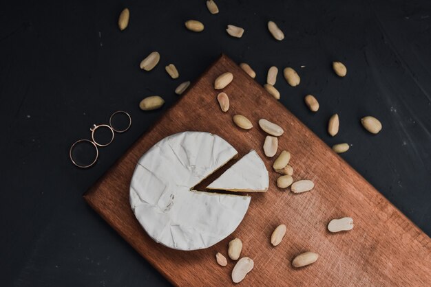 Fromage camembert avec moule et noix et anneaux de mariage sur la planche à découper en bois