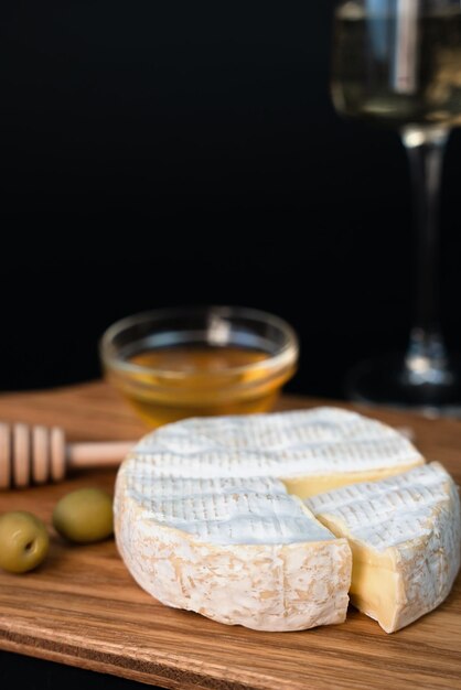 Photo fromage camembert olives miel et verre de vin blanc sur un fond sombre gros plan espace de copie