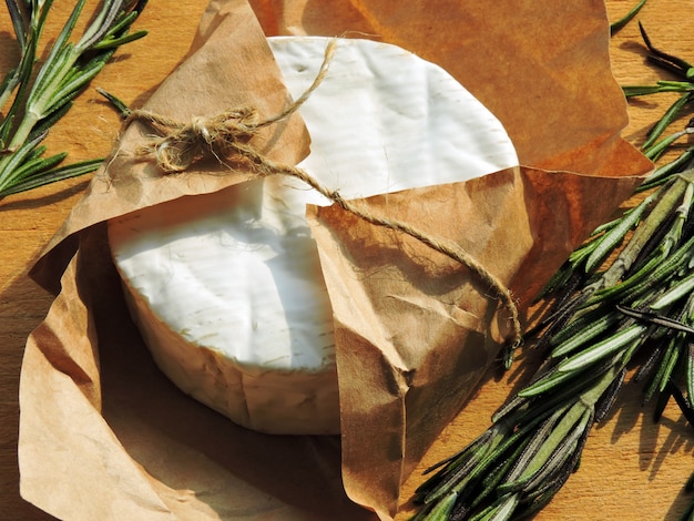 Photo fromage camembert en papier et romarin frais.