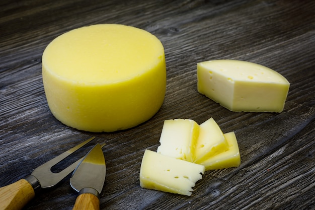 Fromage de chèvre de ferme, fourchette et couteau à fromage sur table en bois