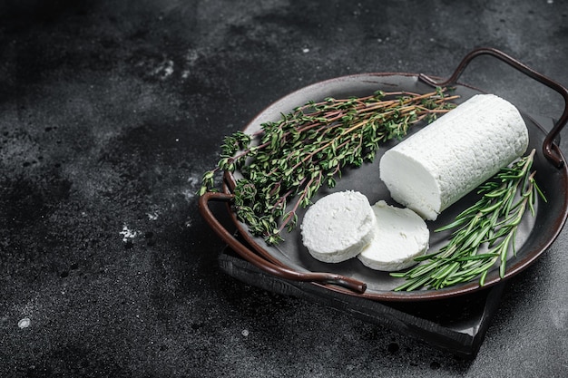 Fromage de chèvre à pâte molle aux herbes sur un plateau Fond noir Vue de dessus Espace de copie