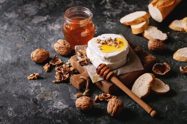 Fromage de chèvre servi avec du miel et des noix sur fond de texture sombre. Copier l'espace