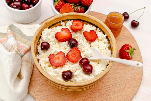 Fromage cottage aux fraises d'été baies de cerisefromage caillé dans un bol avec du mielProduit laitier sain