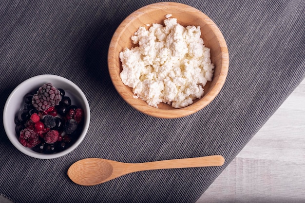 Fromage cottage dans un bol en bois fond sombre baies rouges