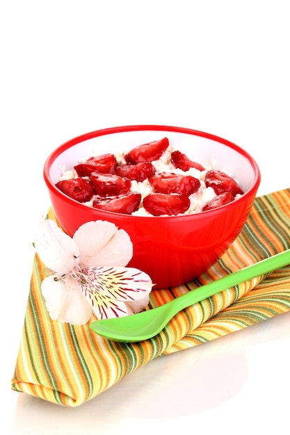 Fromage cottage dans un bol rouge avec des fraises tranchées isolated on white