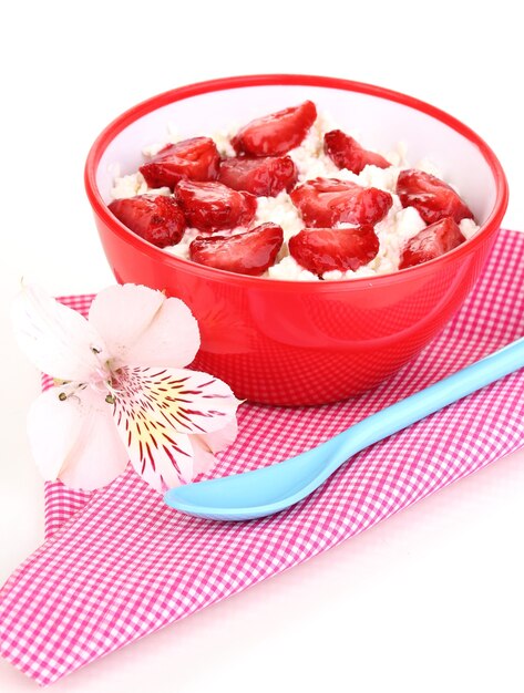 Fromage cottage dans un bol rouge avec des fraises en tranches sur blanc