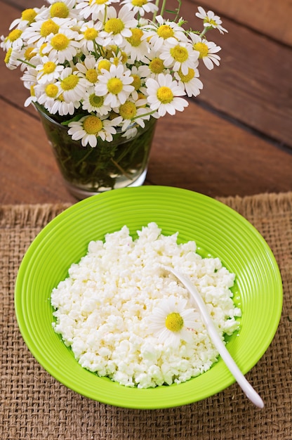 Photo fromage cottage pour le petit déjeuner dans un bol vert sur une table en bois. fermer