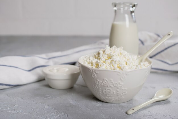 Fromage fermier biologique, caillé dans un bol en céramique blanche, crème sure et lait dans une bouteille