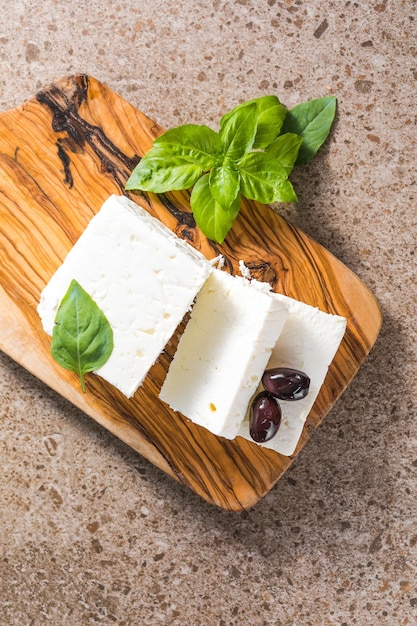 Fromage feta aux olives et basilic sur une planche à découper en bambou Le fromage grec le plus célèbre