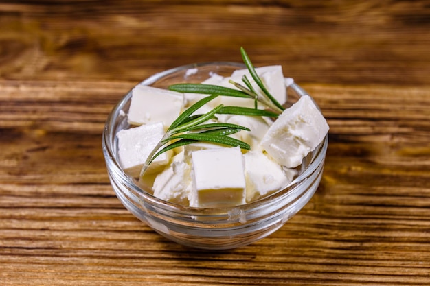 Fromage feta haché et romarin dans un bol en verre sur une table en bois