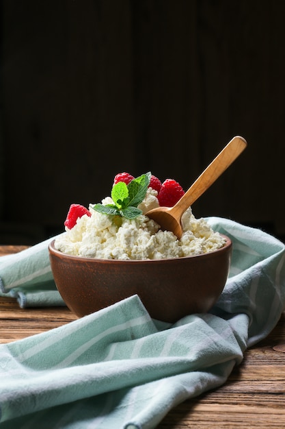 Fromage frais aux framboises et cuillère en bois en terre cuite sur une table en bois