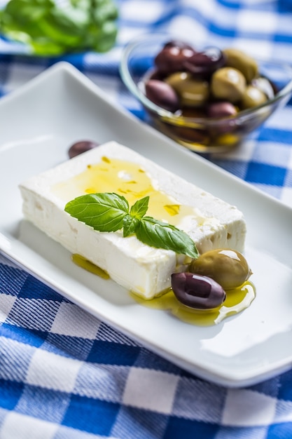 Fromage grec feta avec olives à l'huile d'olive et feuilles de basilic.