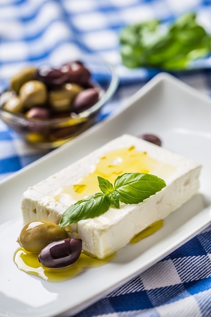 Fromage grec feta avec olives à l'huile d'olive et feuilles de basilic.