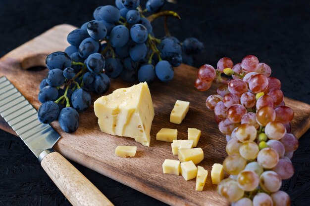 Fromage kachotta sur une planche de bois avec des raisins sur un fond noir