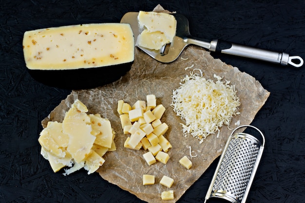 Fromage Kachotta tranché sur un fond noir avec une râpe et un couteau