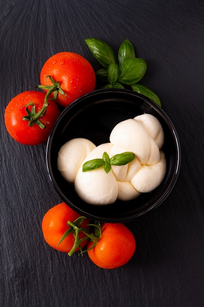 fromage mozzarella bio dans une tasse en céramique noire avec tomates et basilic avec espace de copie