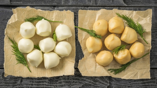 Fromage mozzarella fumé et régulier fraîchement préparé en papier sur une table en bois