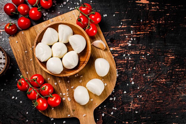 Fromage mozzarella sur une planche à découper avec des épices et des tomates