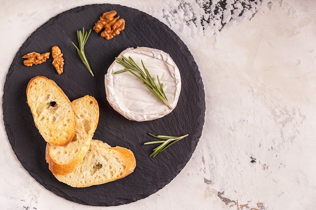 Fromage, noix et pain grillé sur une planche sombre