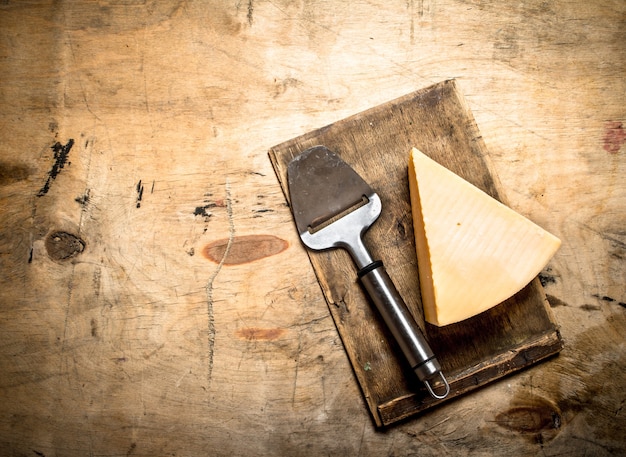 Fromage parmesan avec couteau sur une vieille planche à découper.