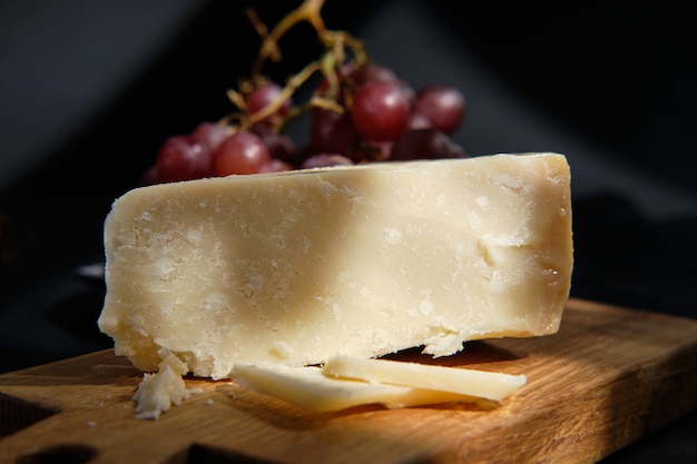 Fromage Parmigiano sur une planche en bois avec des baies de raisin
