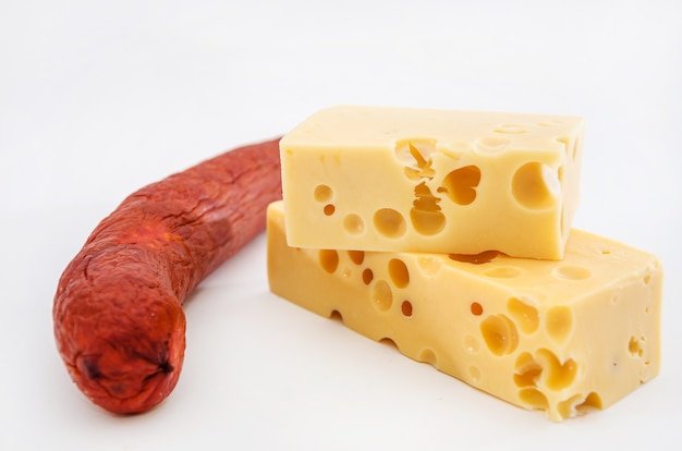 fromage à pâte dure avec des trous et des saucisses fumées sur blanc