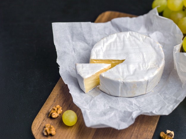 Fromage à pâte molle. Camembert et raisins sur un bois avec des noix. Image vue de dessus avec copie espace