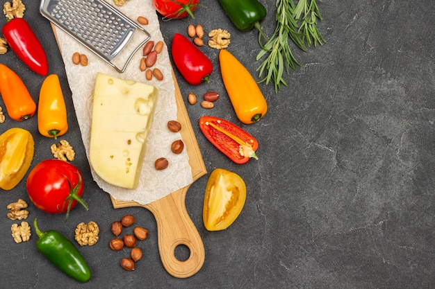 Fromage et râpe, noix, légumes colorés et brins de romarin. Régime équilibré. Espace de copie. Mise à plat. Fond noir.