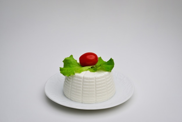 Fromage ricotta avec feuilles de basilic et tomates cerises sur fond blanc Ricotta avec valériane dans un plat blanc Ricotta avec salade dans un plat blanc