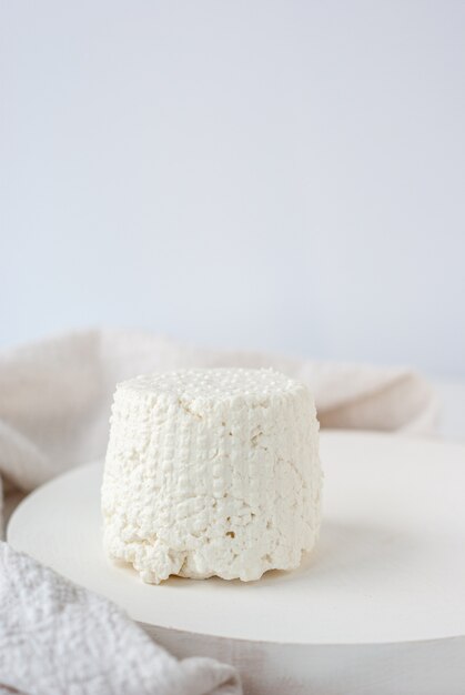 Un fromage ricotta frais sur table en bois blanc