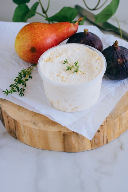 Fromage Ricotta à la pêche, figues et thym sur une planche de bois