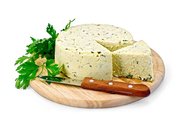 Fromage rond fait maison avec des herbes et des épices coupés, couteau sur une planche de bois ronde isolée sur fond blanc