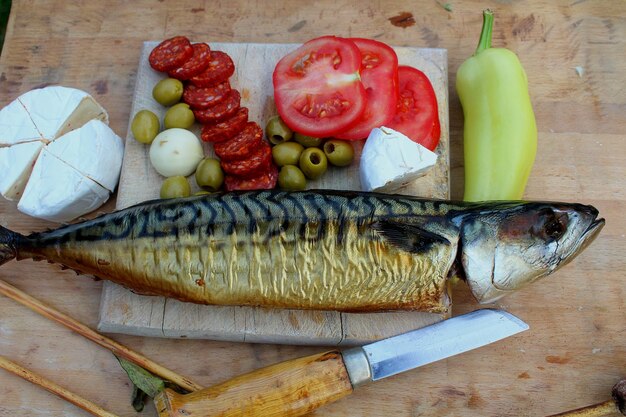 Photo fromage à la saucisse de maquereau fumé et légumes disposés sur une planche à couper